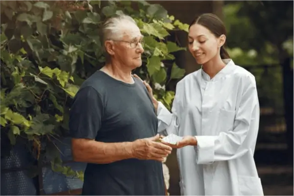 Nurse handing tablets to man outside